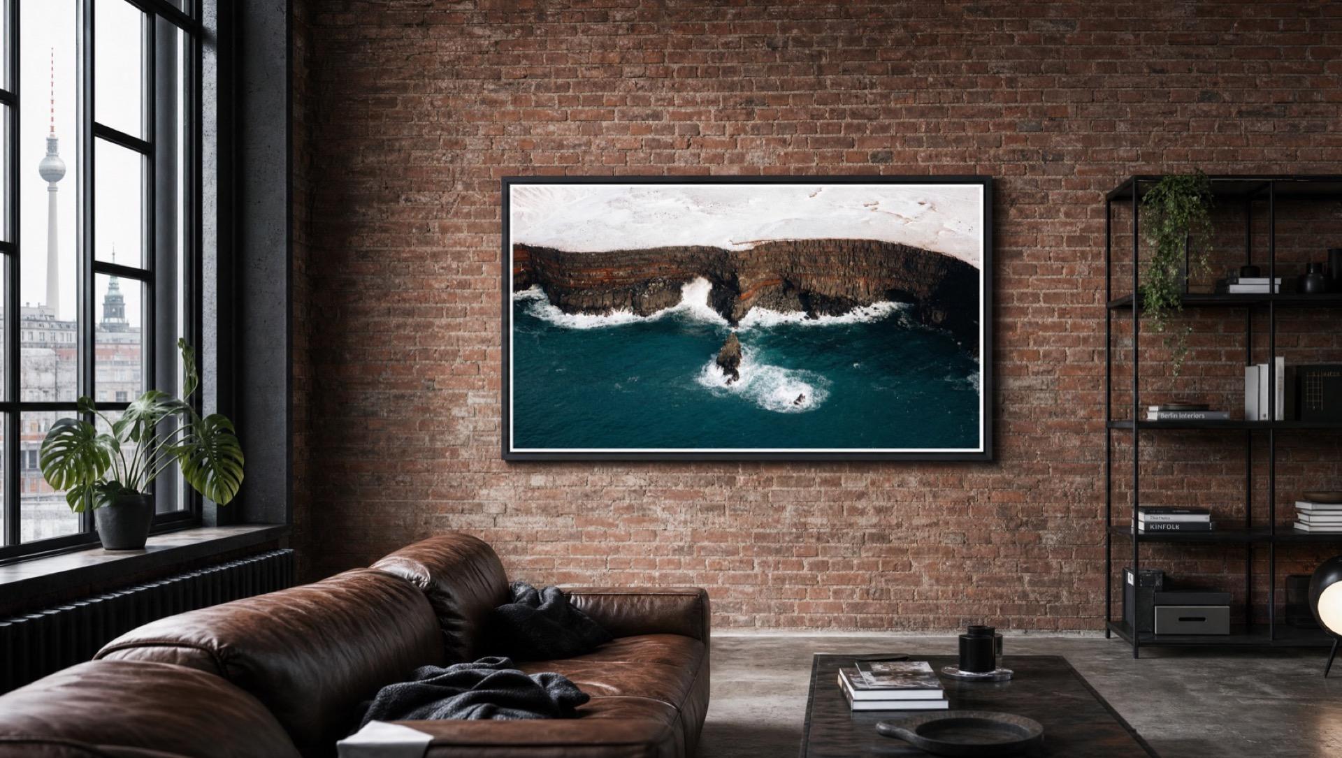 A Samsung The Frame TV showing an ocean cliff photo on the brick wall of a Berlin loft